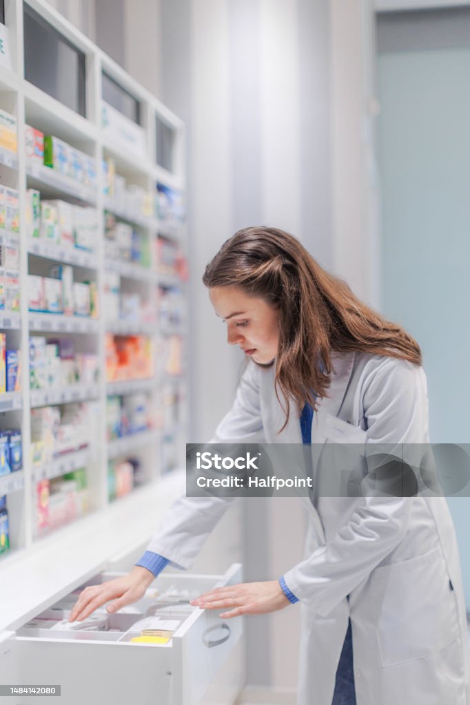 young pharmacist checking medicine stock in a pharmacy.